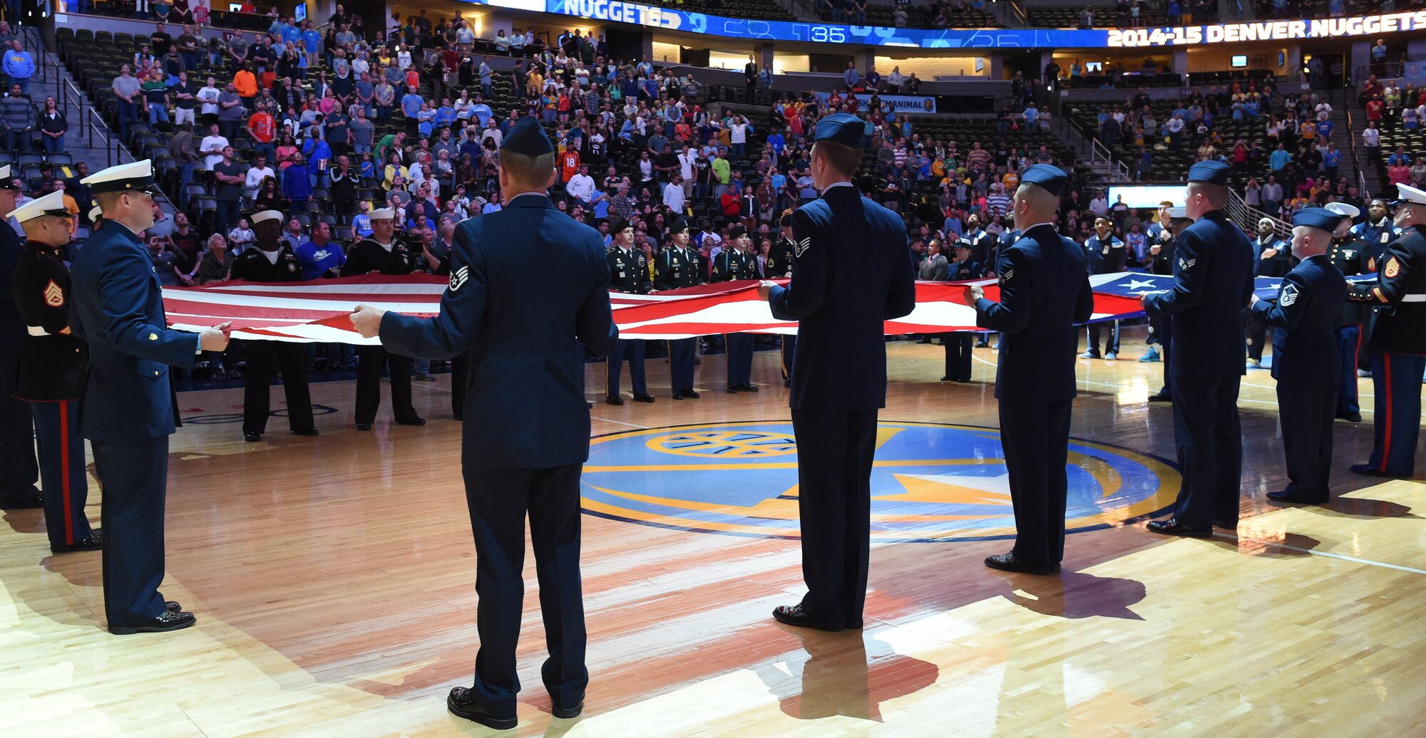 Military members unfurl the American Flag during the national anthem at the Hoops for Troops Night with the Denver Nuggets March 27, 2015, at the Pepsi Center in Denver. Hoops for Troops Night is held to honor military men and women with discounted ticket pricing, a halftime dunk contest and recognition of past, present and future military personnel from all branches. (U.S. Air Force photo by Airman 1st Class Samantha Saulsbury/Released)