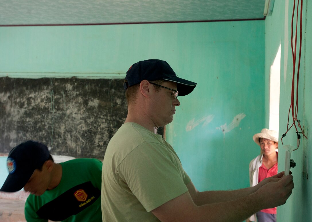 U.S. Air Force Tech. Sgt. Levi Williams wires a switch alongside a Vietnamese soldier at South Tinh Phong primary school during an engineering project in the Quang Ngai province, Vietnam, March 26, 2015. 
