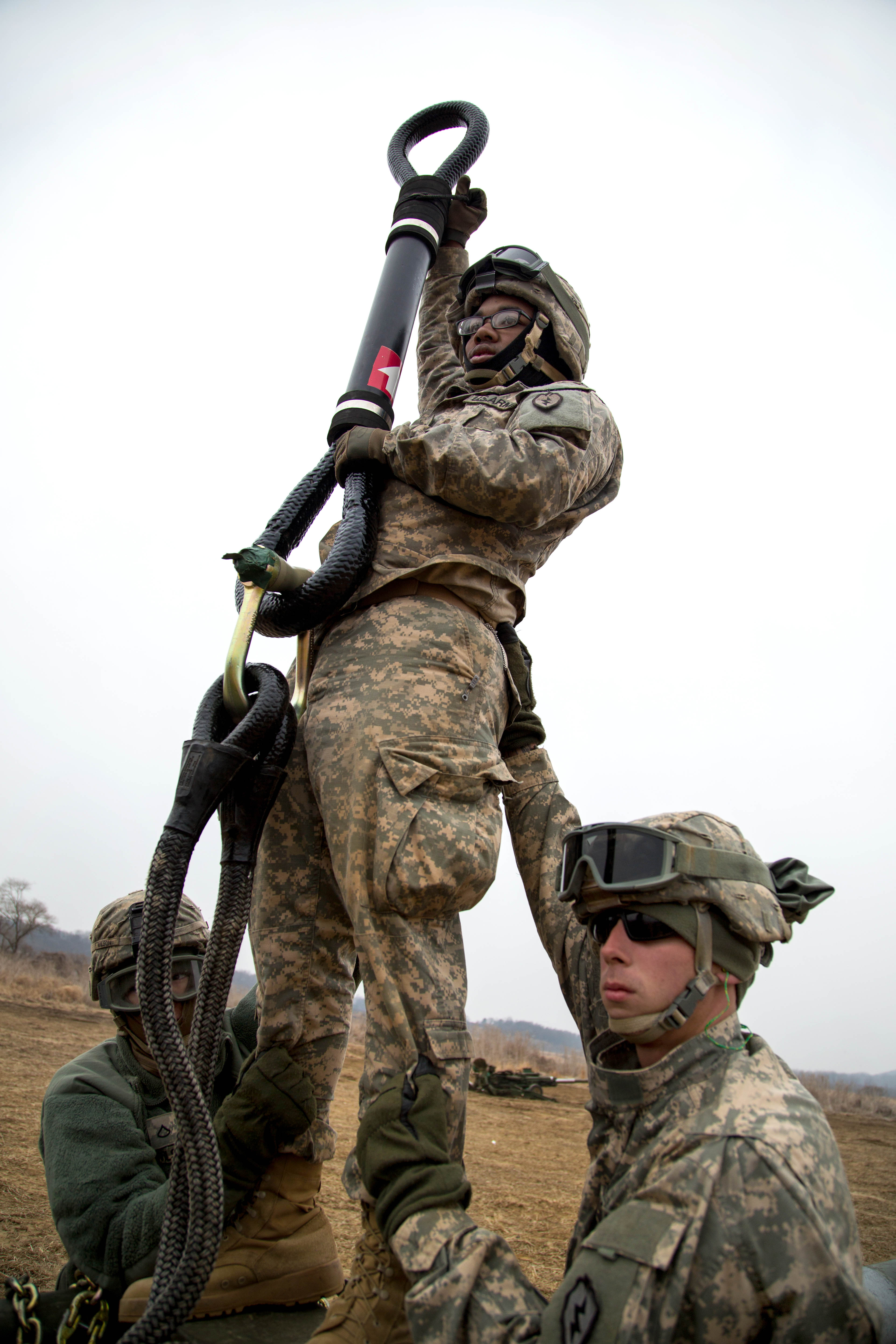 U.S. soldiers prepare to hook a howitzer system to a CH47 Chinook helicopter for slingload