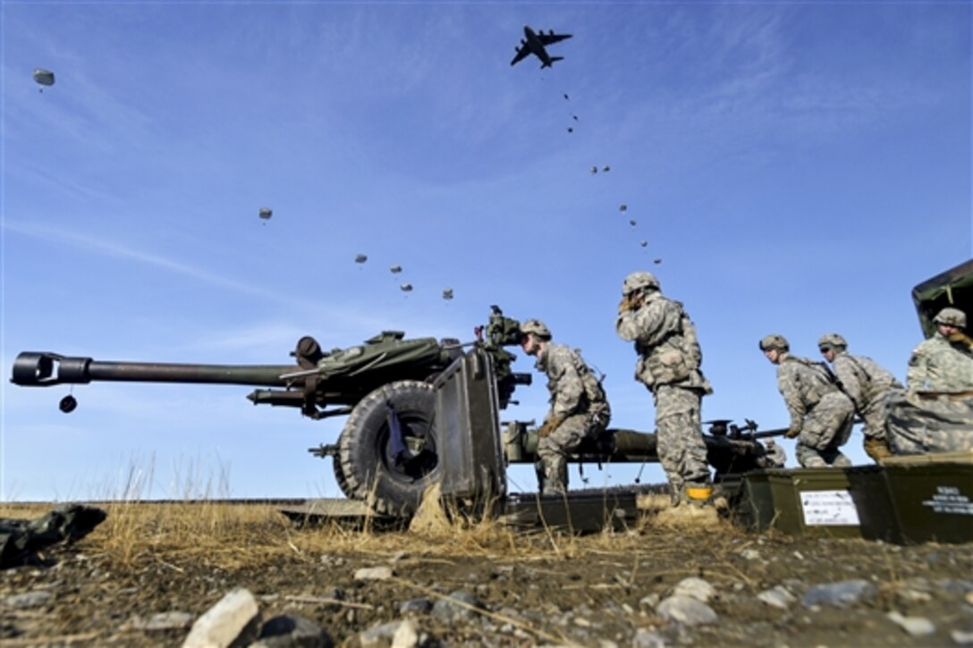 Paratroopers move an 105-mm howitzer into firing position as other paratroopers conduct a parachute assault during Operation Spartan Valkyrie at Malamute drop zone on Joint Base Elmendorf-Richardson, Alaska, March 20, 2015.