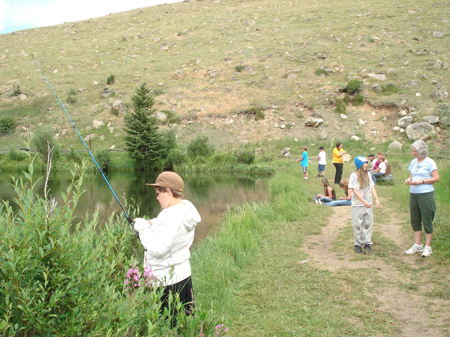 Robin Gorsuch, the state youth coordinator for the Wyoming National Guard, far right, speaks with a youth program participant, while other children of military families go fishing at a youth camp, August 2011. Although deployments have gone down, family program support officials don’t see a correlated decrease in the need for services.