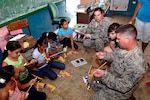 Tech. Sgt. Dorothy Lanthier, a personnel specialist deployed from 177th Fighter Wing of the New Jersey Air National Guard, and Staff Sgt. Josh Lazarski help children assemble rubber-band airplanes at the Sansonsito School in Panama July 12, 2010. Lanthier and Lazarski are assigned to 820th Expeditionary RED HORSE Squadron.