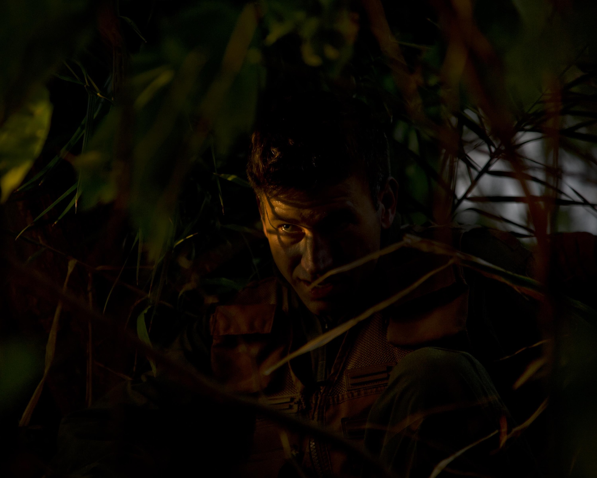 Maj. Dan Allen takes cover in the brush during combat survival training March 26, 2015, at Joint Base Pearl Harbor-Hickam, Hawaii. Allen, who is a pilot evaluator for the 96th Air Refueling Squadron, led a team of four during four hours of training that is designed to simulate the aircrew going down in a hostile environment. The aircrew uses teamwork to conceal their location, evade opposition forces and practice proper recovery procedures. (U.S. Air Force photo/Tech. Sgt. Aaron Oelrich)