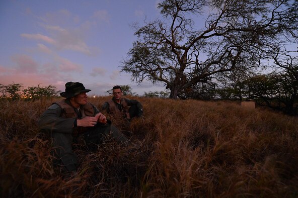 Capt. Matt Savage and Senior Airman Kenneth Stricker wait for two team members to return during combat survival training March 26, 2015, at Joint Base Pearl Harbor-Hickam, Hawaii. This training simulates the aircrew going down in a hostile environment. The aircrew uses teamwork to conceal their location, evade opposition forces and practice proper recovery procedures. Savage is a pilot and Strickler is a boom operator for the 96th Air Refueling Squadron. (U.S. Air Force photo/Tech. Sgt. Aaron Oelrich

