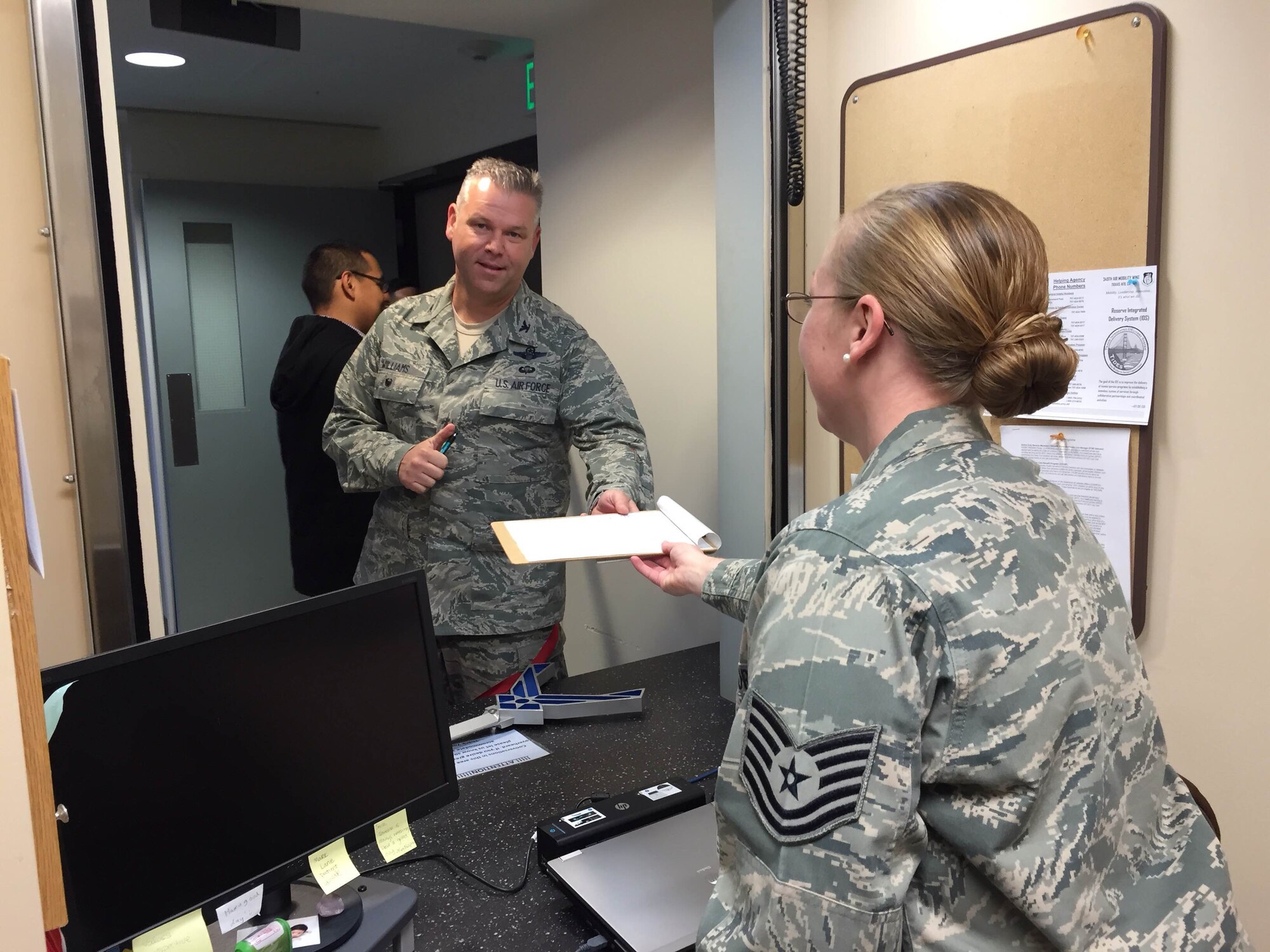 TRAVIS AIR FORCE BASE, Calif. -- Col. Williams photo: Col. Patrick Williams, 349th Air Mobility Wing vice commander, receives a questionnaire from Reserve Component Liaison Tech. Sgt. Nicole Nagle. The ribbon cutting Mar. 23, 2015, marked the opening of the Reserve Component Liaison desk in David Grant Medical Center. Located on the second floor at the first window in the Patient Services Center, the liaison will help solve billing problems and establish eligibility for Reservists to receive care. (Courtesy photo/Released)