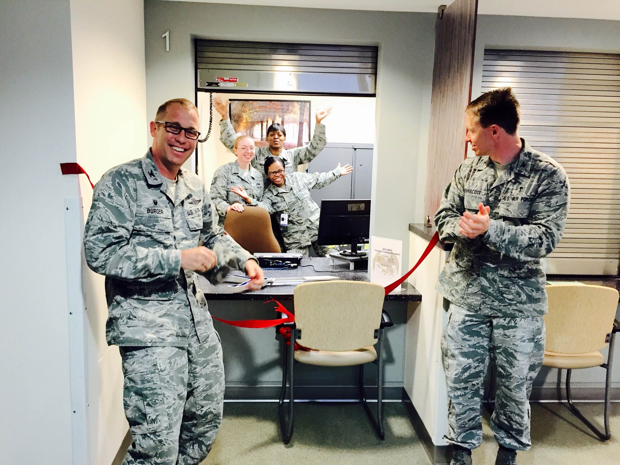 TRAVIS AIR FORCE BASE, Calif. -- Col. Matt Burger, 349th Air Mobility Wing commander, and Col. Matthew Wonnacott, 60th Medical Group deputy commander, cut the ribbon to open the Reserve Component Liaison desk in David Grant Medical Center Mar. 23. As the window opens, cheering behind the desk are, from the right: Master Sgt. Delmora Holman-McClendon, 349th Aerospace Medicine Squadron health services administrator, Senior Master Sgt. Helena McGhee, 349th AMDS superintendent, and Tech. Sgt. Nicole Nagle, 349th AMDS Reserve Component Liaison.