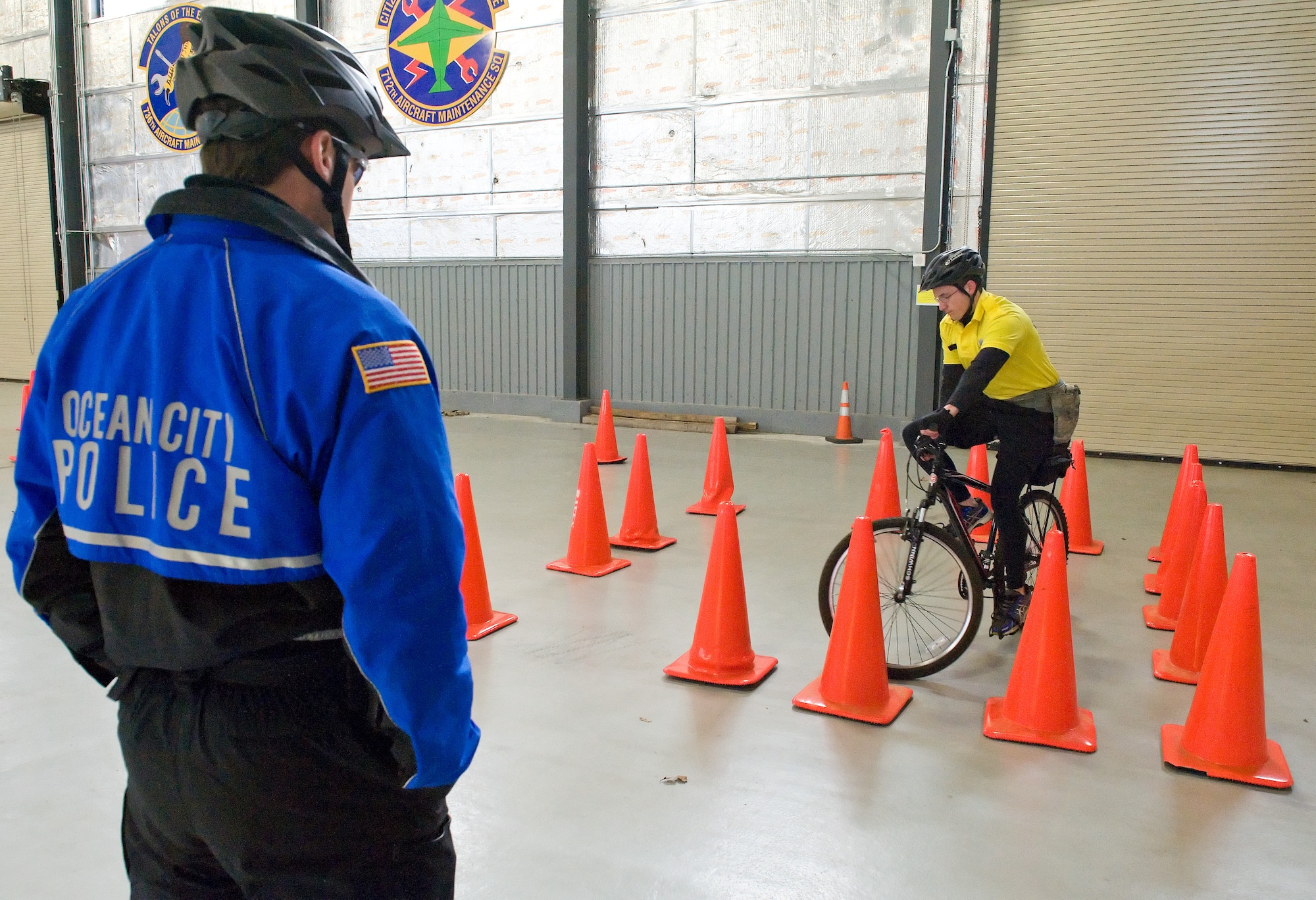 Corporal Richard Wawrzeniak, Ocean City Police Department, Md. left, observes Airman 1st Class David Bischoff, 436th Security Forces Squadron response force leader, right, ride his mountain bike at slow speed within a box-shaped area March 19, 2015, at Dover Air Force Base, Del. Bischoff and six other bike patrol members of the 436th SFS had to accomplished both clockwise and counter-clockwise versions of this slow-speed, confined area bike test as part of their International Police Mountain Bike Association bike patrol certification. (U.S. Air Force photo/Roland Balik)