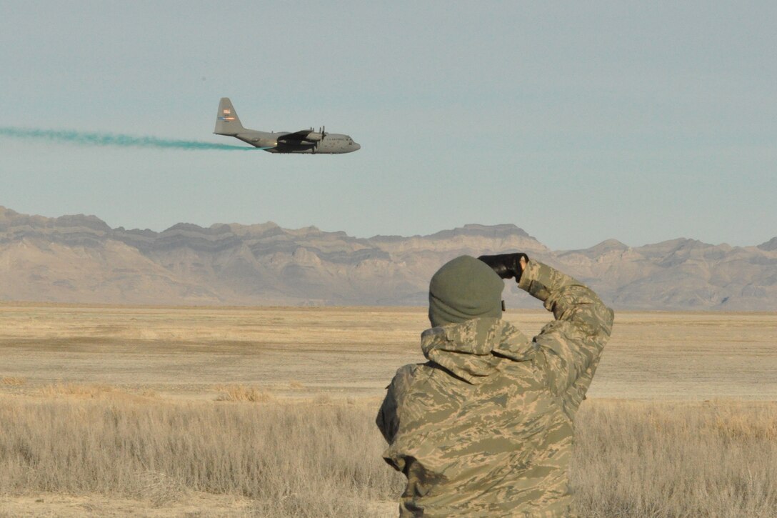 HILL AIR FORCE BASE, Utah – Air Force Reserve Tech. Sgt. Rick Lisum, 910th Airlift Wing Public Affairs Photojournalist based at Youngstown Air Reserve Station, Ohio, photographs a C-130 Hercules aircraft conducting aerial spray operations at an altitude of approximately 100 feet above the ground over a target site on the Utah Test and Training Range near here, March 18, 2015. The C-130 assigned to 910th Airlift Wing based at Youngstown Air Reserve Station, Ohio and home to the Department of Defense’s only large area, fixed wing aerial spray capability, is flying at the low altitude to control the placement of herbicide onto the selected target areas while conducting a two-week aerial spray mission over UTTR, March 9 – 20, 2015, to eliminate unwanted ground-covering invasive weeds. U.S. Air Force photo by Senior Airman Rachel Kocin