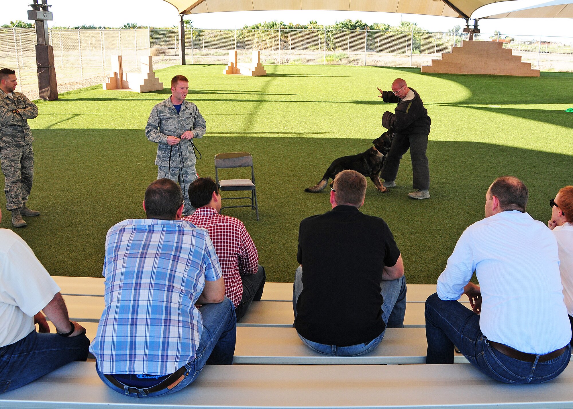 Staff Sgt. Scott Emmick, 56th Security Forces Squadron military working dog trainer, orchestrates a demonstration March 27 while Staff Stg. Kurtis Buchawieki, 56th SFS dog handler, tries to fend off Crash, 56th SFS MWD and members from the Entrepreneurs Organization watch during a tour at Luke Air Force Base, Ariz. (U.S. Air Force photo by Tech. Sgt. Louis Vega Jr.)