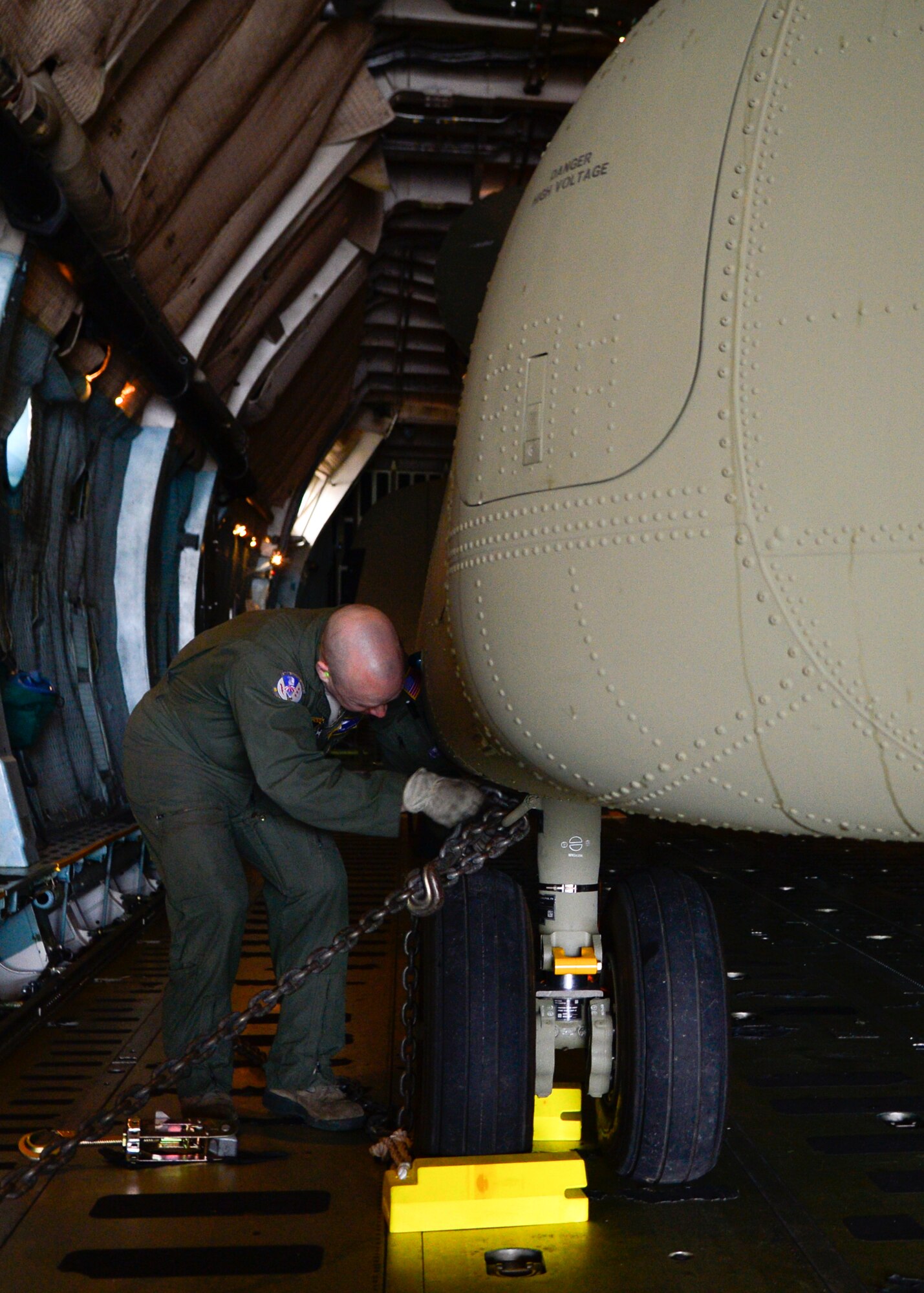 Master Sgt. Ryan Johnson, 337th Airlift Squadron loadmaster from Westover Air Reserve Base, Mass., chains down a Chinook CH-47F helicopter inside of a C-5B Galaxy March 27, 2015, at Dover Air Force Base, Del. The crew is delivering two new Chinook helicopters to the Australian Army. (U.S. Air Force photo/Airman 1st Class William Johnson)
