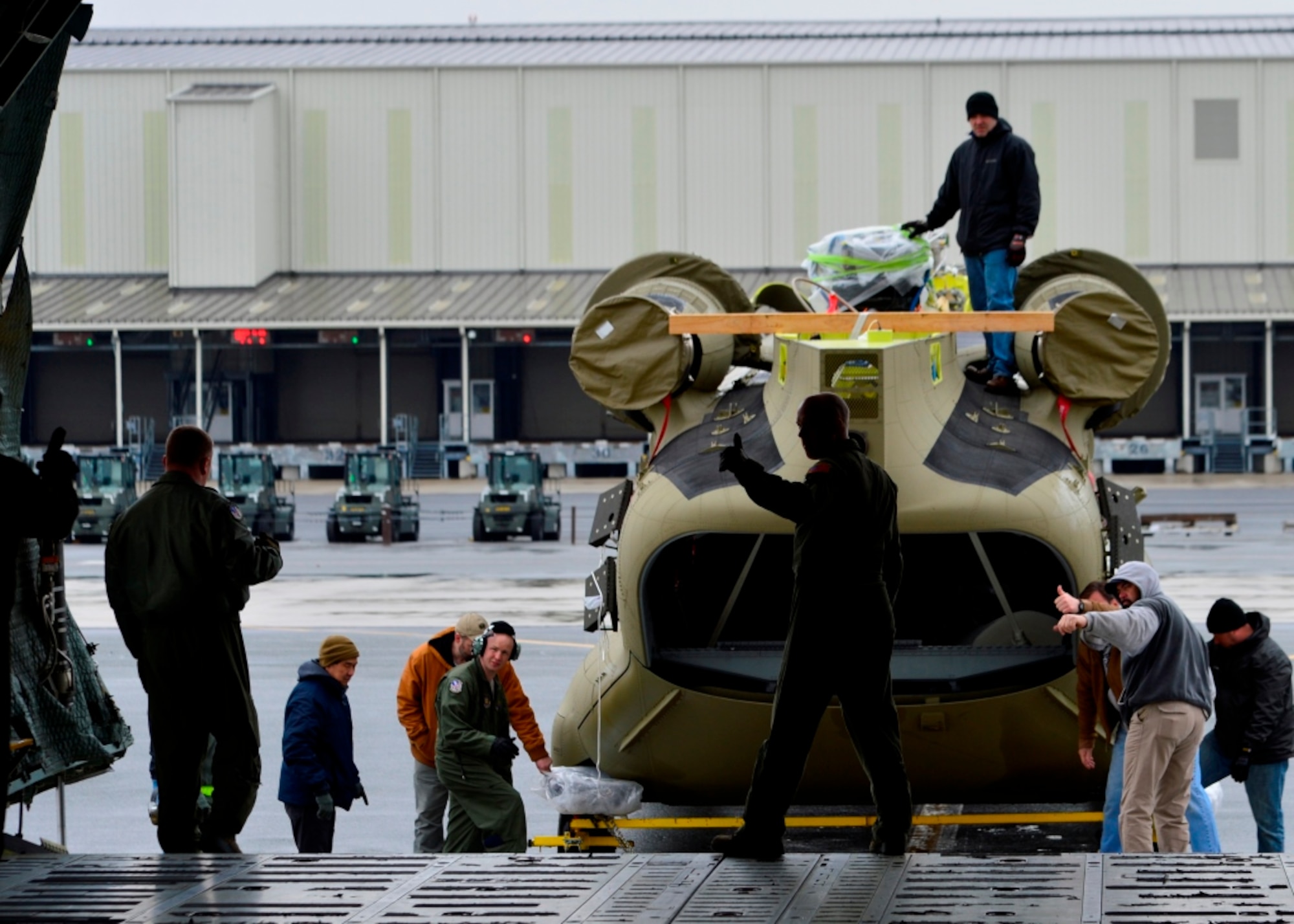 Master Sgt. Ryan Johnson, 337th Airlift Squadron loadmaster from Westover Air Reserve Base, Mass., signals to another loadmaster to activate a wench while loading a Chinook CH-47F helicopter onto a C-5B Galaxy March 27, 2015, at Dover Air Force Base, Del. The crew loaded two helicopters weighing approximately 24,000 pounds per aircraft. (U.S. Air Force photo/Airman 1st Class William Johnson)