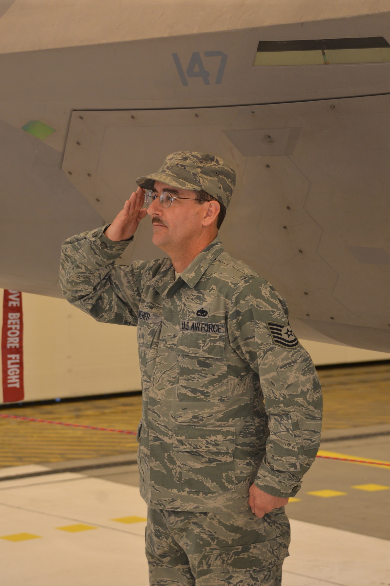 Tech. Sgt. Robert Breher, F-22 dedicated crew chief assigned to the 477th Aircraft Maintenance Squadron salutes Col. David Piffarerio after presenting him with the 477th Fighter Group flag ship, during the unit’s change of command ceremony Friday at Hangar 25.  (US Air Force photo by Tech. Sgt. Dana Rosso)