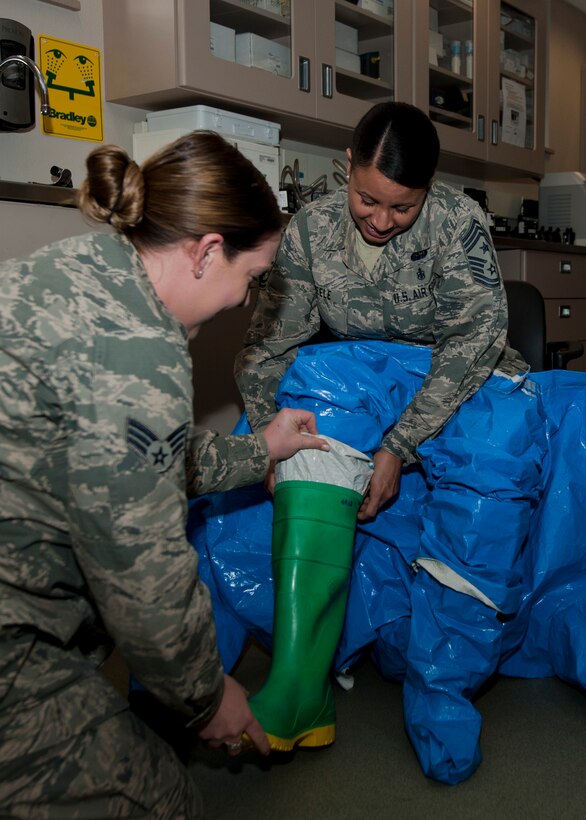 PETERSON AIR FORCE BASE, Colo. – Senior Airman Meagan Blankenship, 21st Medical Group Bioenvironmental Engineering technician, assists Chief Master Sgt. Idalia Peele, 21st Space Wing command chief, into a Level A fully-encapsulating suit used to protect the wearer from chemical agents and splash hazards, at the 21st Bioenvironmental Engineer squadron, March 18. This experience was part of a newly implemented shadow program, which gives Peele the opportunity to better know the Airmen of the 21st Space Wing, and to allow junior Airmen a chance to see the “big picture” and better understand how and why base-impacting decisions are made. (U.S. Air Force photo by Staff Sgt. J. Aaron Breeden)
