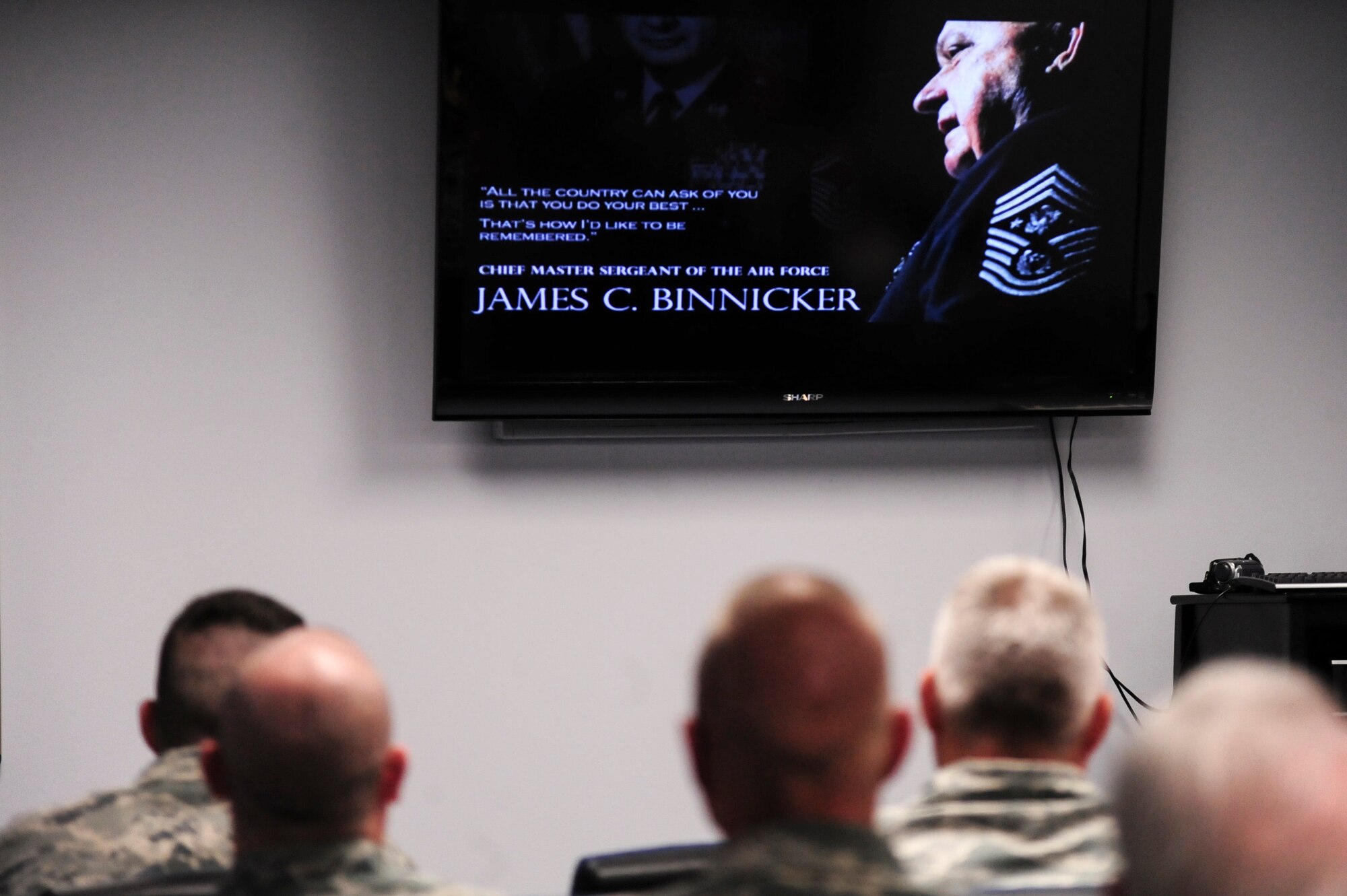 Members of Team Seymour watch a video presentation during a remembrance ceremony for retired Chief Master Sgt. of the Air Force James C. Binnicker, the ninth CMSAF, March 27, 2015, at Seymour Johnson Air Force Base, North Carolina. Binnicker left a lasting impression on the Air Force by implementing the Enlisted Performance Report as well as the feedback system. (U.S. Air Force photo/Senior Airman Brittain Crolley)