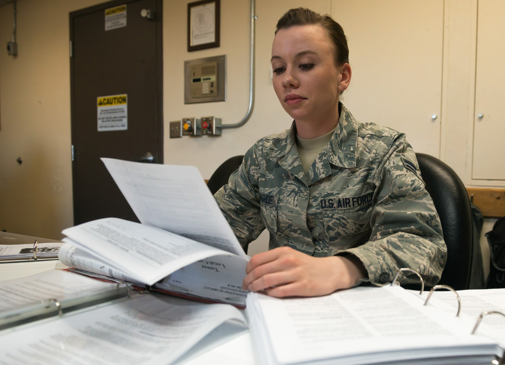 Airman 1st Class Cassandra Donohoe, 366th Operations Support Squadron air traffic controller apprentice, flips through a stack of training material at Mountain Home Air Force Base, Idaho, March 18, 2015. Small libraries of training information litter the tower where she works. (U.S. Air Force photo by Airman Connor J. Marth/RELEASED)