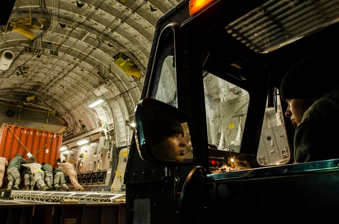 Air Force Senior Airman Seth Allen operates a cargo loader as airmen move equipment on a C-17 Globemaster III transport jet at the Transit Center at Manas, Kyrgyzstan, March 14, 2014. An Air Force team from the Air Transportability Test Loading Activity received the 2014 Distinguished Achievement Award for updating a military standard for internal aerial delivery in fixed-wing aircraft to enhance support of multinational operations. U.S. Air Force photo by Senior Airman Ross Alexander Whitley