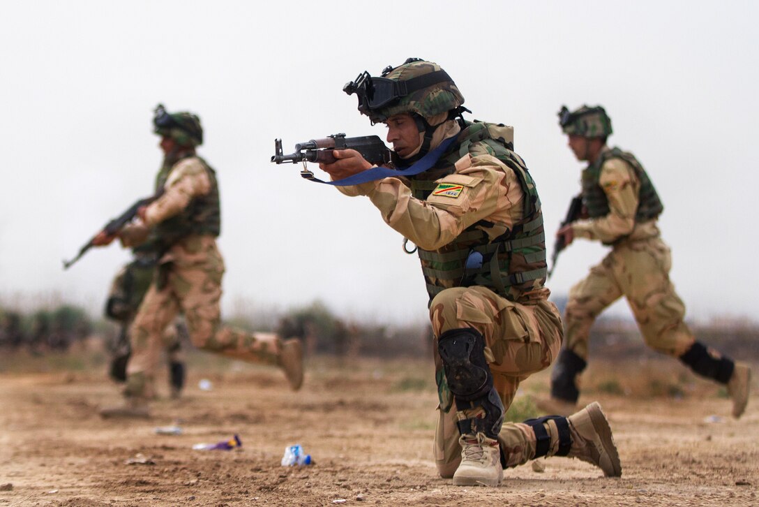 An Iraqi army soldier provides security as other Iraqi soldiers cross a road during a training exercise on Camp Taji, Iraq, March 24, 2015.