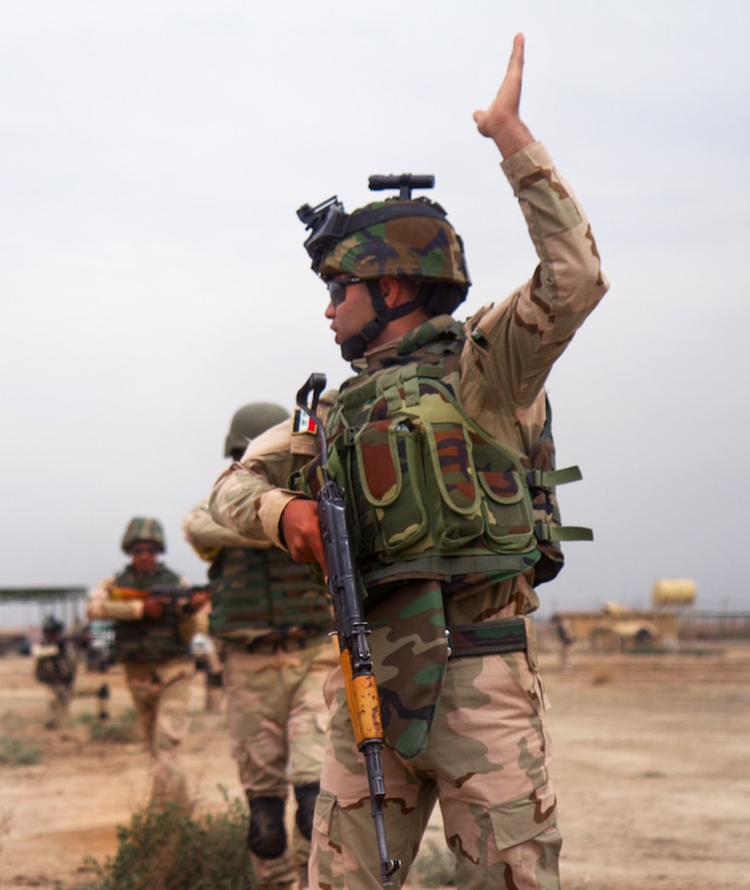 An Iraqi army soldier uses a hand signal to direct other soldiers behind him into the proper formation during a training exercise on Camp Taji, Iraq, March 24, 2015.