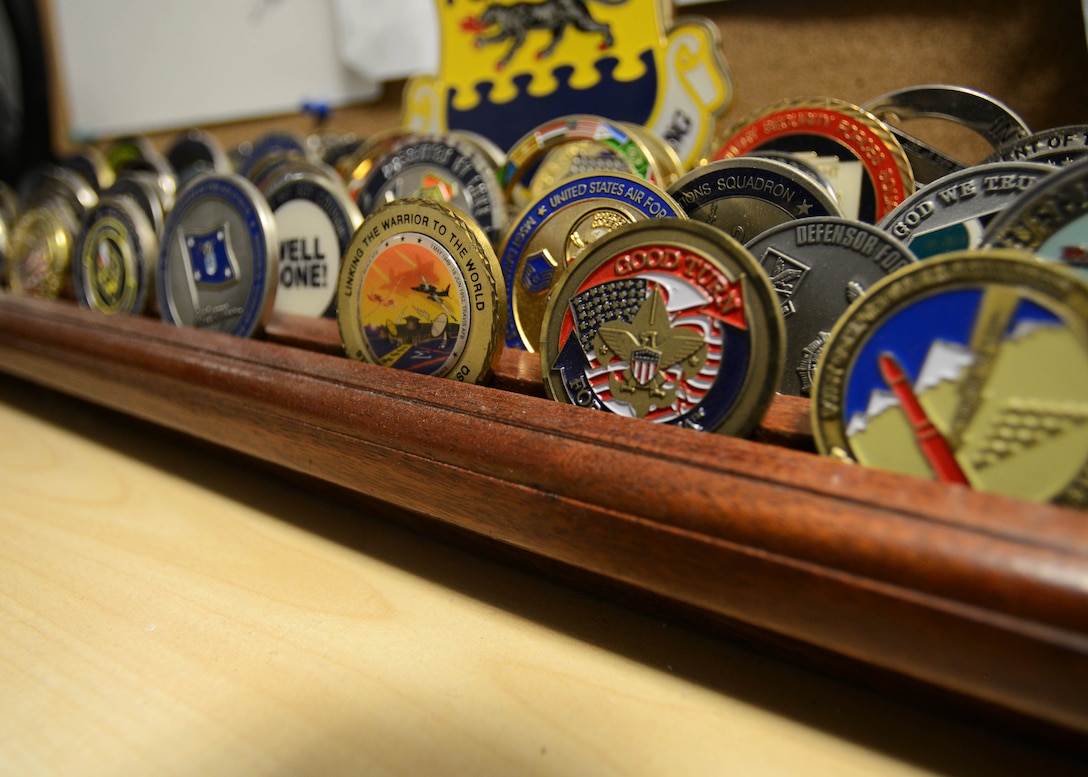The history of the challenge coins dates back to World War II, when an American pilot was shot down and captured in Germany. His identity was proven and life saved when he revealed a bronze medallion, with his flying squadron emblem. (U.S. Air Force photo by Airman 1st Class Deana Heitzman/Released) 