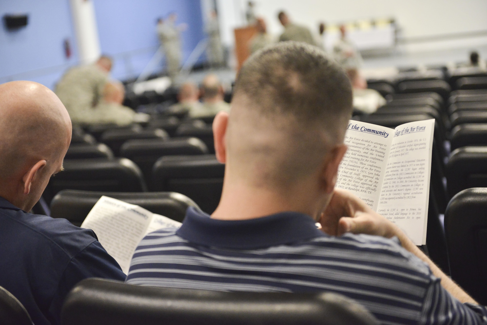 Co-workers and friends fill the theater and read the list of graduates prior to a Community College of the Air Force graduation ceremony April 28, 2015, at the Blatchford-Preston Complex theater Al Udeid Air Base, Qatar. Continued off-duty education in the military can be difficult; the support of supervisors, co-workers and friends has led to over 420,000 degrees since 1972.  (U.S. Air Force photo/Staff Sgt. Alexandre Montes)