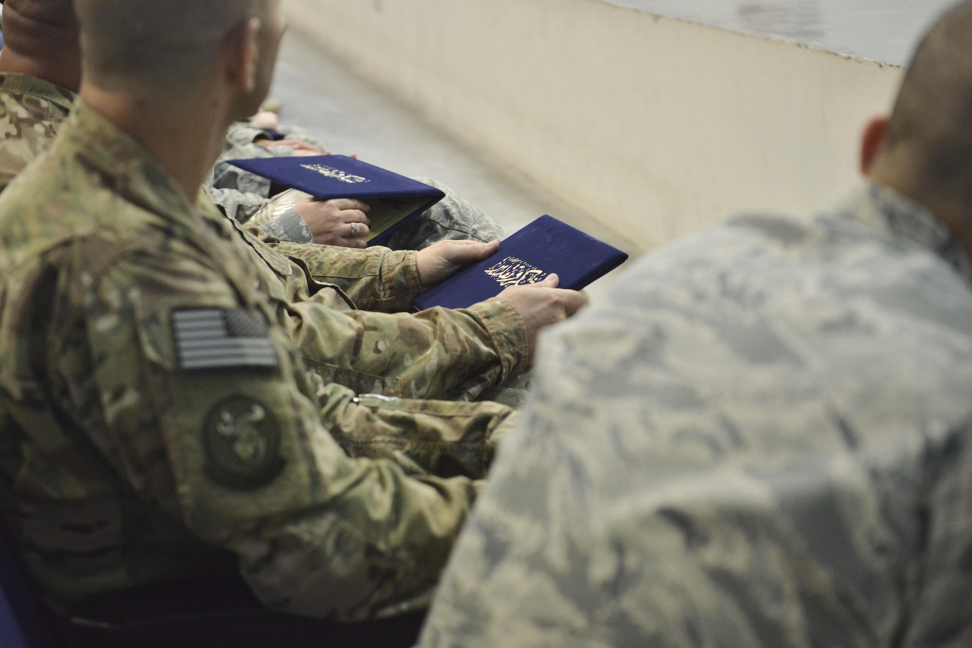 Graduates hold their Community College of the Air Force diplomas after the recognition ceremony April 28, 2015, at the Blatchford-Preston Complex theater Al Udeid Air Base, Qatar. Graduations are held annually across the Air Force. Depending if the graduate is available to attend, certificates are also mailed to their location. This was the third graduation to ever happen at Al Udeid since being introduced here in 2014. Two graduations are held throughout the year to better accommodate deployed members. (U.S. Air Force photo/Staff Sgt. Alexandre Montes)