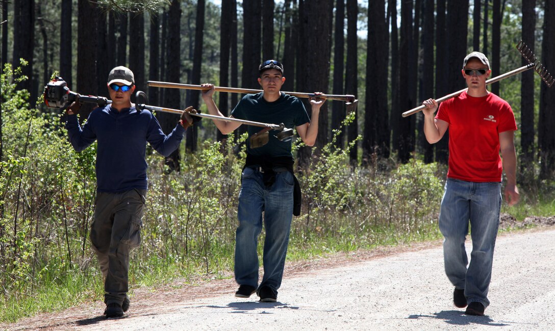 Corporal Randy Bautista, left, Cpl. Luis E. Barbosa, center, and Cpl. Abram E. Brown return from raking underneath trees that were marked to indicate where endangered woodpeckers nest in the Croatan National Forest, New Bern, North Carolina, April 22, 2015. Hundreds of Marines and Sailors of Marine Corps Air Station Cherry Point, North Carolina, participated in celebrating the Single Marine Program’s 20th anniversary by volunteering at various locations around the community. Bautista, Barbosa and Brown are Marines with Headquarters and Service Company, Marine Wing Communications Squadron 28.