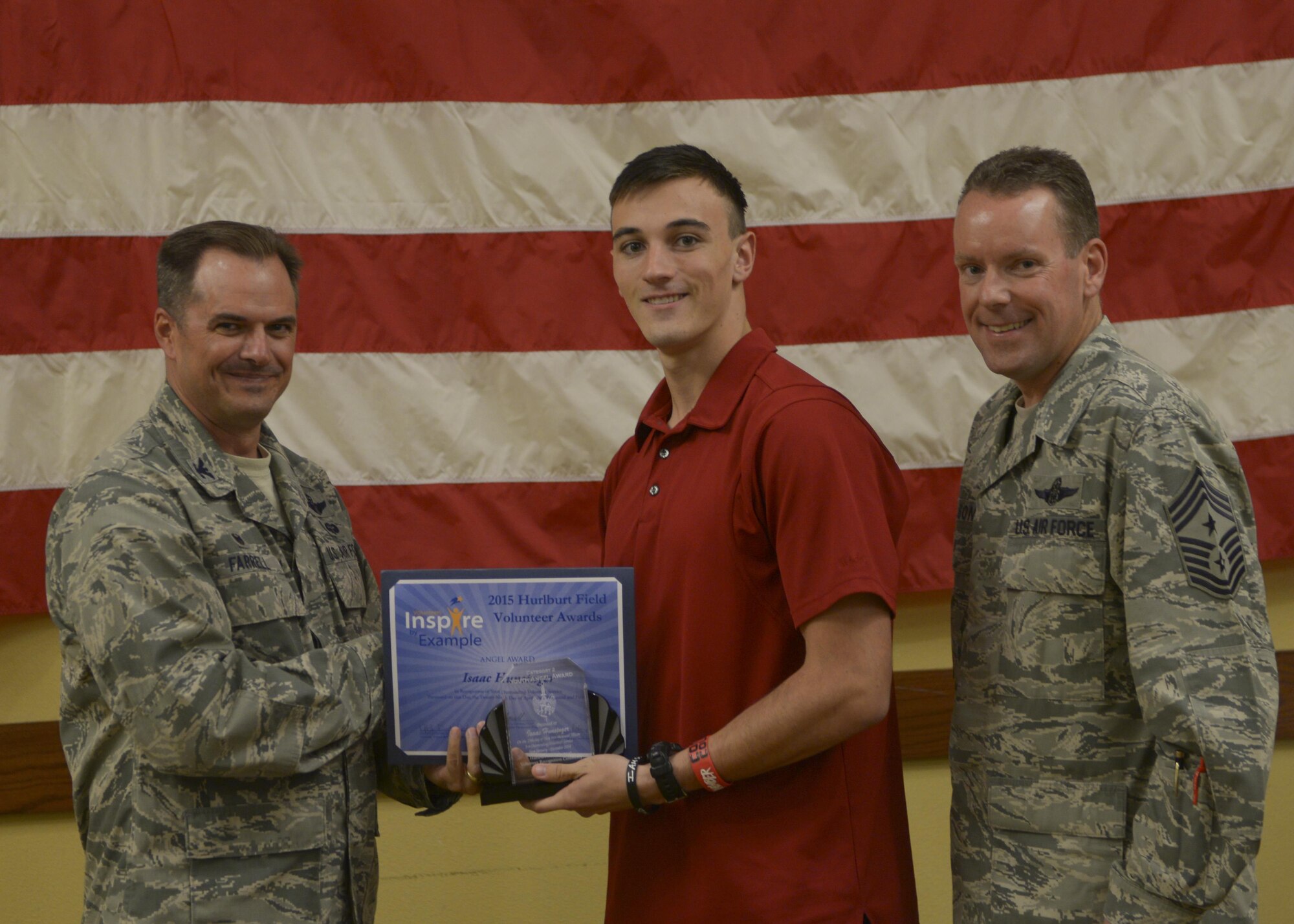 Col. Sean Farrell, 1st Special Operations Wing commander and Chief Master Sgt. Cory Olson, 1st SOW command chief, present Isaac Hunsinger the youth Angel Award at the Soundside Club on Hurlburt Field, Fla., April 29, 2015. The Angel Award is a prestigious award that was established in 1988 by Mrs. Eunice Welch, wife of retired Air Force Chief of Staff Gen. Larry D. Welch. (U.S. Air Force photo/Senior Airman Christopher Callaway)