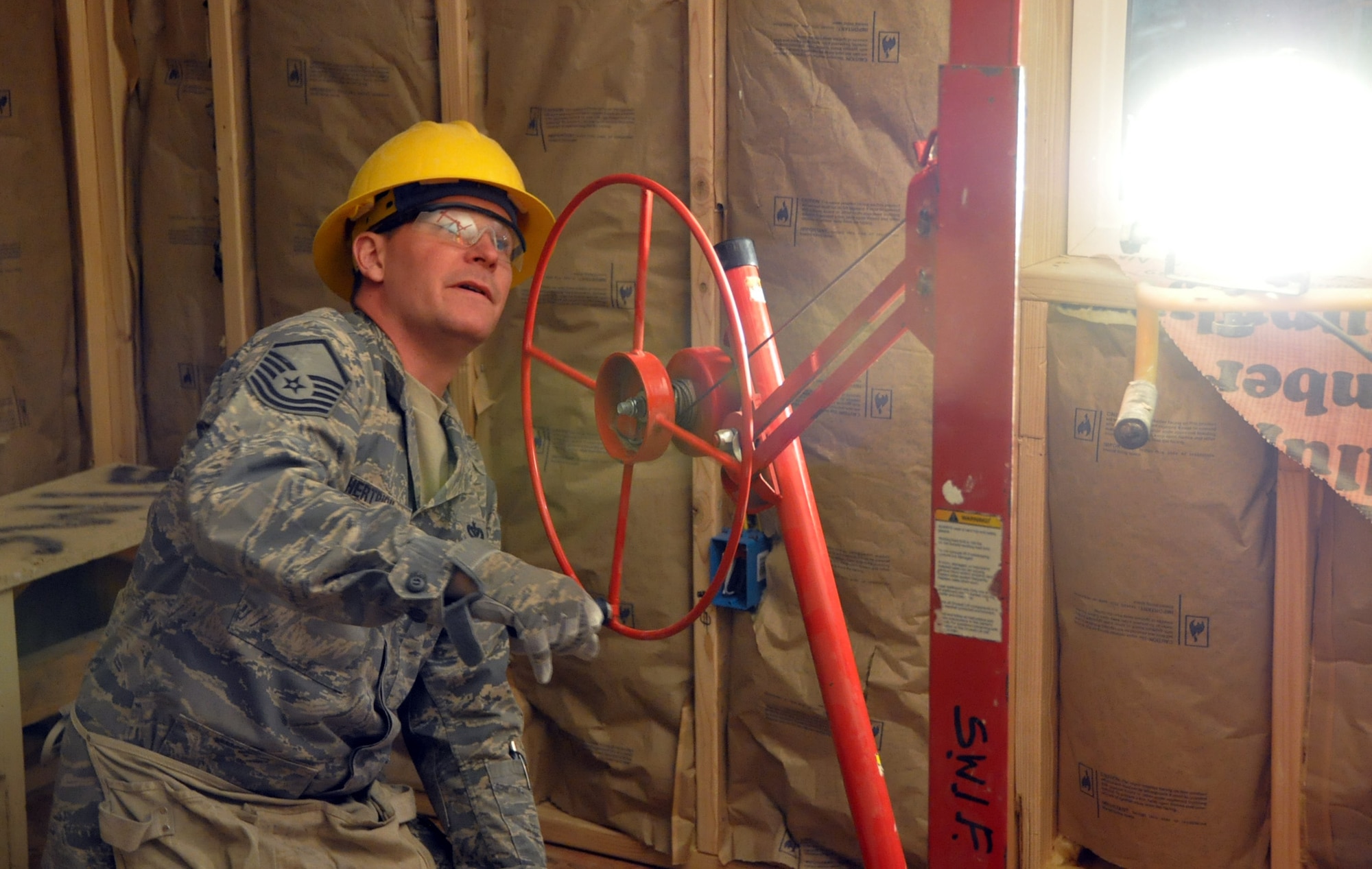 Master Sgt. Hertrich, an operations specialist with the 911th Airlift Wings’ Civil Engineer Squadron, uses a lift system to help put sheets of dry wall on the ceiling of a home being built for the local Navajo Nation of Gallup, N.M., April 24. (U.S. Air Force Photo by Senior Airman Joseph E. Bridge)