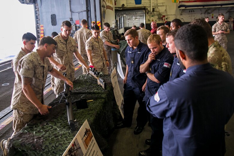 U.S. Marine Corps Lance Cpl. Charlie Wheeler, right, a motor transportation operator with the 22nd Marine Expeditionary Unit (MEU), gives a presentation on the M2 .50 caliber machine gun to British Royal Navy sailors with the HMS Lancaster during a tour aboard the amphibious assault ship USS Wasp (LHD 1) while out at sea April 30, 2015. Marines and U.S. Navy Sailors with the 22nd MEU from Marine Corps Base Camp Lejeune, N.C., participated in Navy Week 2015 in New Orleans April 23-29 and Fleet Week Port Everglades, Fla., May 4-10. The purpose of Navy Week was to showcase the strength and capabilities of the Navy-Marine Corps team through tours, static displays and community relations events, providing the public the opportunity to meet and interact with Marines and Sailors. (U.S. Marine Corps photo by Sgt. James R. Smith/Released)