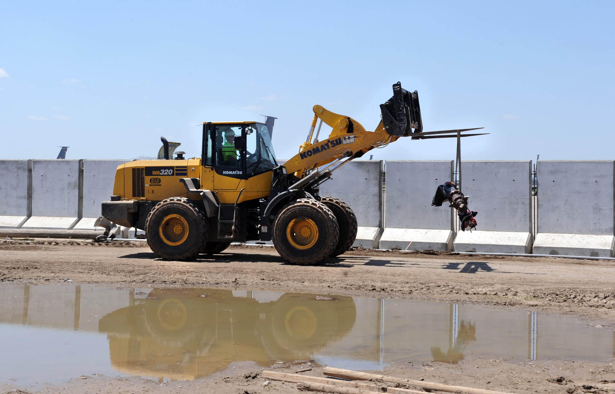 A wheel loader hauls an old pipe away from the KC-46A Pegasus hangar construction site, April 30, 2015, at McConnell Air Force Base, Kan.  Three hangars are being built to house the new aircraft and will have the capability of storing six KC-46As. Hangars 1124 and 1125 are scheduled for completion by the end of the year and Hangar 1126 is scheduled for completion in 2017. (U.S. Air Force photo by Staff Sgt. Rachel Waller) 