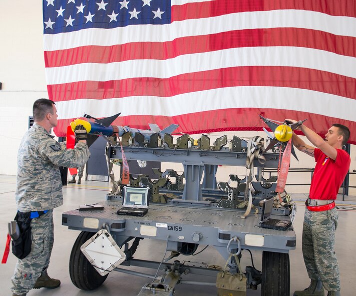 U.S. Air Force Tech. Sgt. John Chapman, 74th Aircraft Maintenance Unit weapons load team chief, left, and Airman 1st Class Matthew Gogal, 75th Aircraft Maintenance Unit weapons load crew member, prepare to load AIM-9 Sidewinder missiles during the weapons load crew of the quarter competition April 24, 2015, at Moody Air Force Base, Ga. Unit observers evaluated each weapons load crew on four categories: a 25-question test, a dress and appearance inspection, a tool box inspection and the loading the aircraft. (U.S. Air Force photo by Airman Greg Nash/Released)