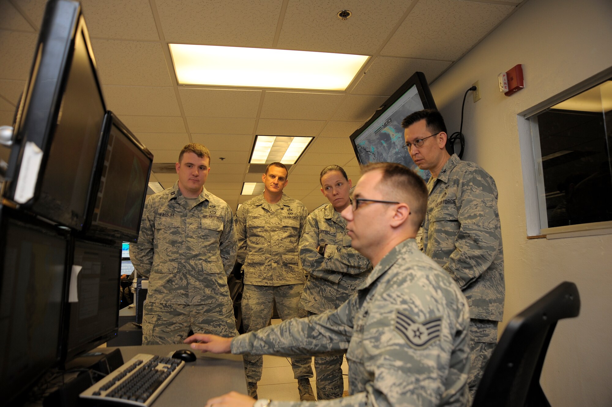 Staff Sgt. Anthony Hall, 25th Operational Weather Squadron standardizations and evaluation Airman, shows Col. William J. Carle, 557th Weather Wing commander, and Chief Master Sgt. Terri Grebel, 557th Weather Wing command chief, the different modeling solutions for forecasting aviation hazards over rough terrain in the Western continental U.S. at Davis-Monthan Air Force Base, Ariz., April 23, 2015.  The 25th OWS is a tenant unit at Davis-Monthan AFB and its higher headquarters is the 577th WW at Offutt Air Force Base, Neb. (U.S. Air Force photo by Staff Sgt. Angela Ruiz)