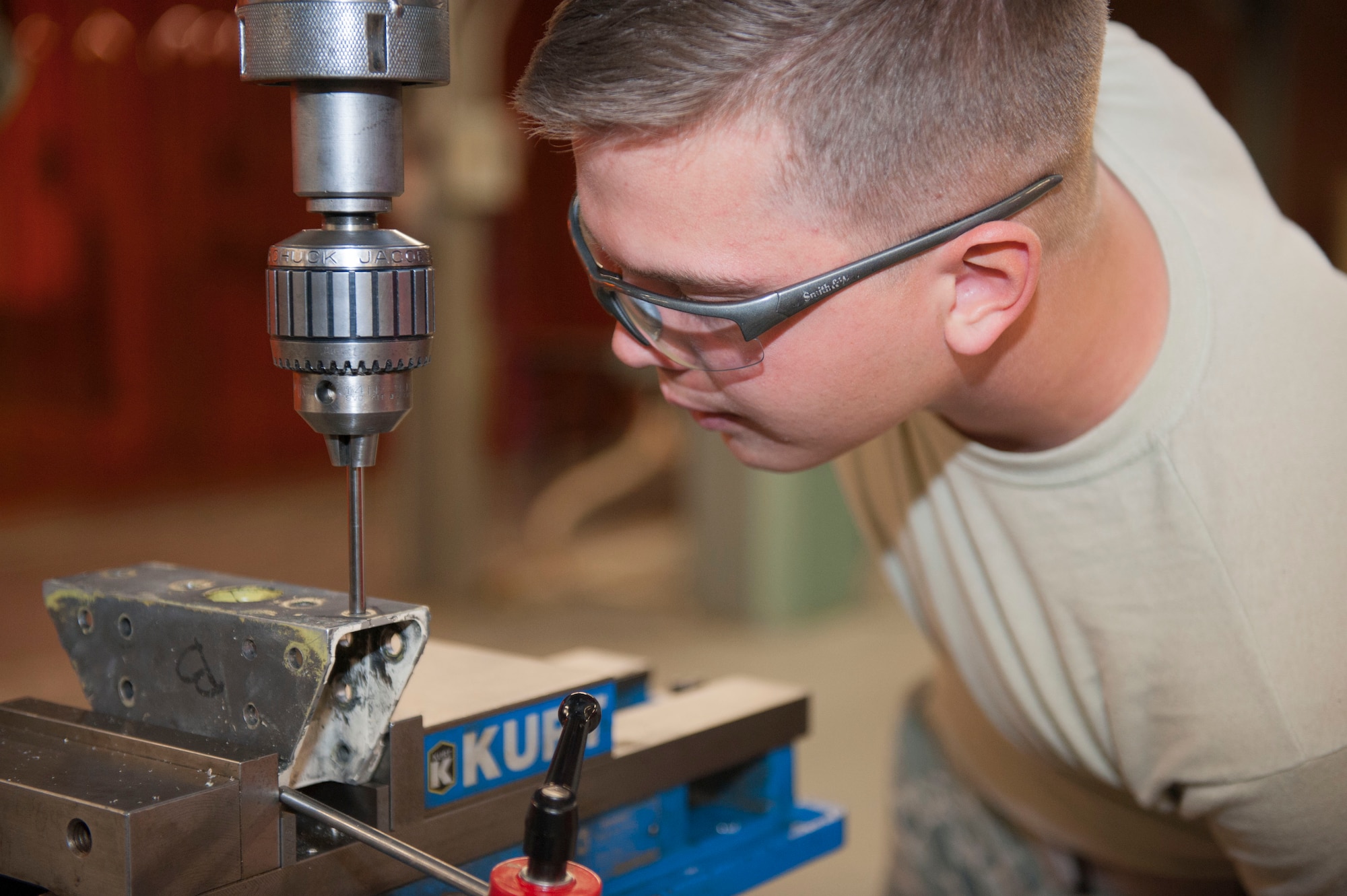 Airman 1st Class Joshua Gorman, 49th Maintenance Squadron Aircraft Metals Technology apprentice, inspects and measures the holes on an old flap mount for an F-16 Fighting Falcon at Holloman Air Force Base, N.M. April 30, 2015. Gorman used a mill to drill and ream holes into the new flap mount, which will replace the old ones on the tail flaps of an F-16. The Aircraft Metals Tech shop is also responsible for supporting Flight line operations, all back shops and any agency needing precision metal work done. (U.S. Air Force Photo by Staff Sgt. E'Lysia A. Wray/Released)