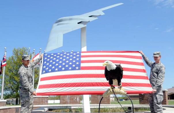 Senior Airmen Justin Holden (left)  and Dane Anderson (right), 509th Contracting Squadron specialists, hold the U.S. flag during a re-enlistment ceremony at Whiteman Air Force Base, Mo., April 23, 2015. Lewis, a 13 year-old Bald Eagle also attended the ceremony as the special guest. Lewis flew during the St. Louis Cardinals opening day at Busch Stadium. (U.S. Air Force photo by Staff Sgt. Alexandra M. Longfellow/Released)