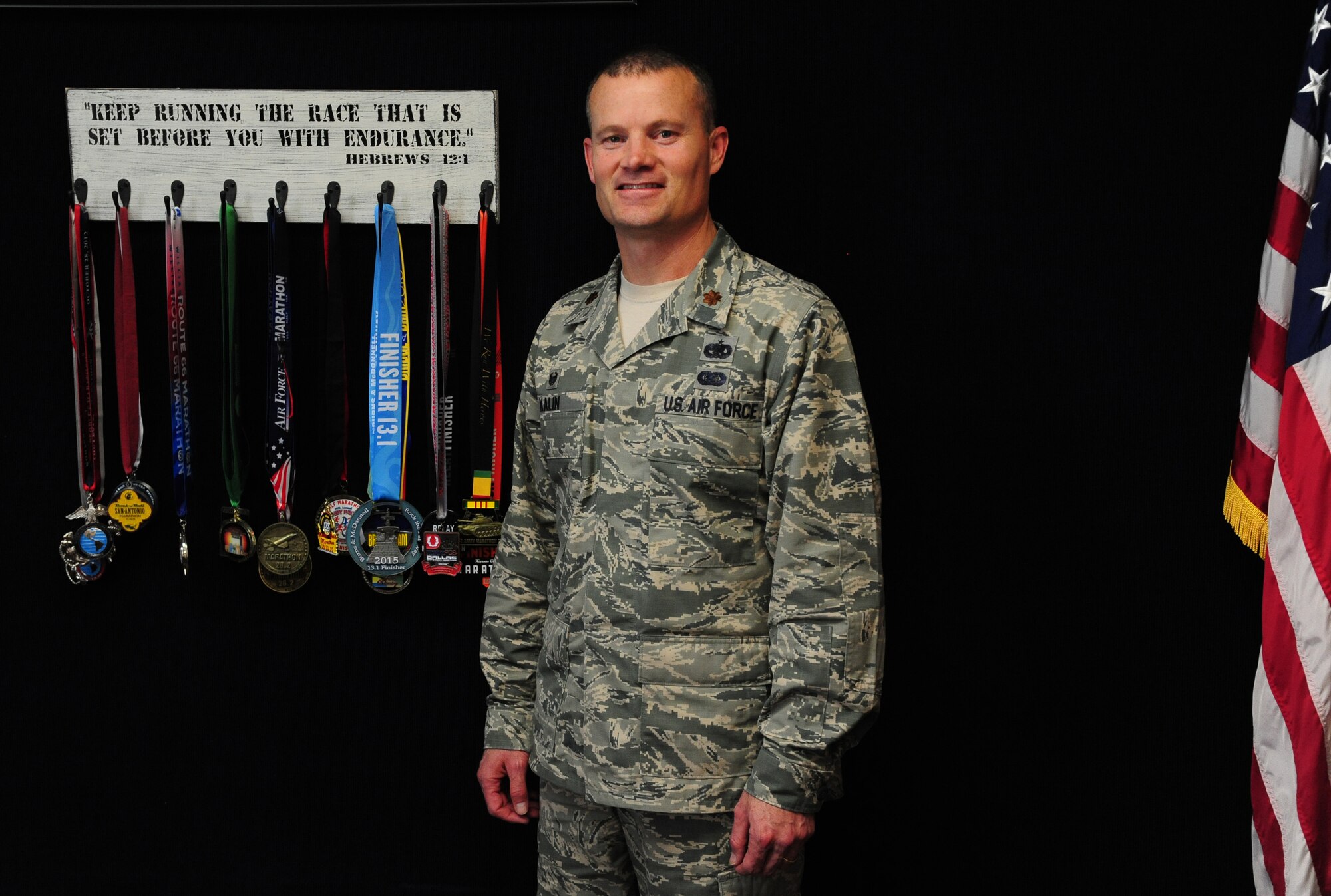 Maj. Jason Kalin, 509th Logistics Readiness Squadron commander, poses in front of his running medals at Whiteman Air Force Base, Mo., April 16, 2015. Kalin has participated and completed one Ultramarathon (63.75 miles), 16 marathons, five half-marathons, two Bataan Death Marches and numerous 10 milers, 10Ks and 5Ks. To culminate his tour at Whiteman, Kalin is taking part in his last race as the commander of the 509th LRS, the Striker Life Half Marathon. (U.S. Air Force photo by Senior Airman Keenan Berry/Released)