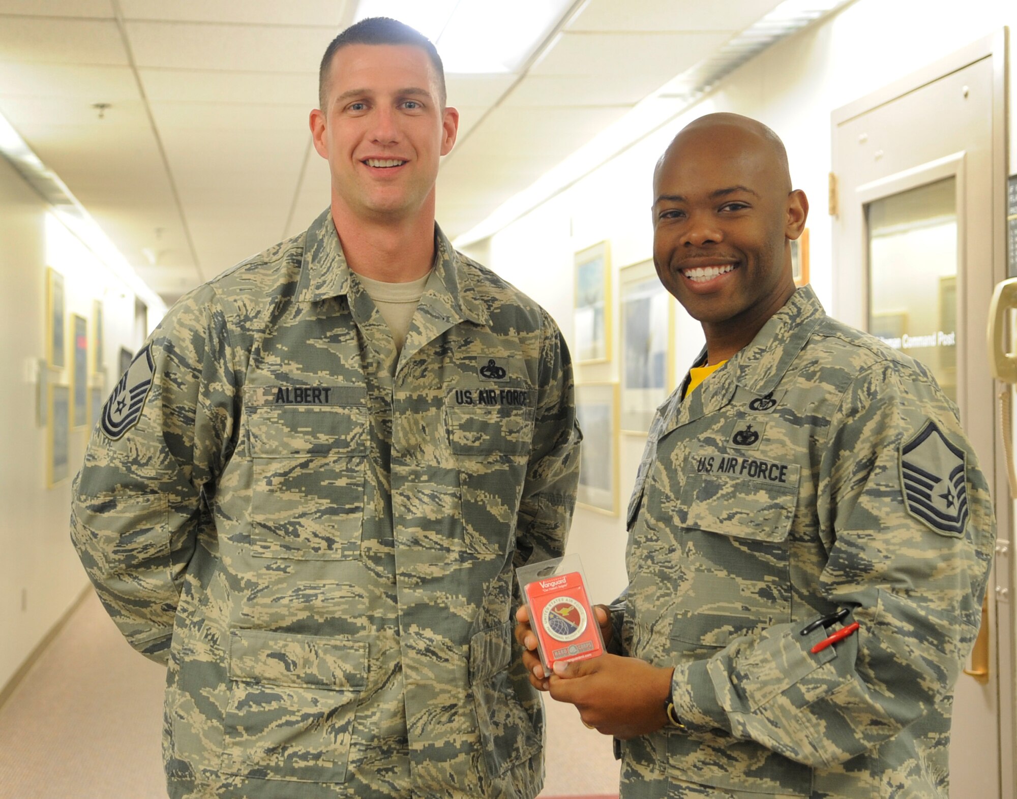 U.S. Air Force Master Sgt. Dennis Caldwell Jr. (right) poses with Master Sgt. Josef Albert, Airman Leadership School commandant, after being notified of his selection for a developmental special duty at Whiteman Air Force Base, Mo., April 24, 2015.  Caldwell is slated to become the newest Whiteman ALS commandant. (U.S. Air Force photo by Staff Sgt. Alexandra Longfellow/Released) 