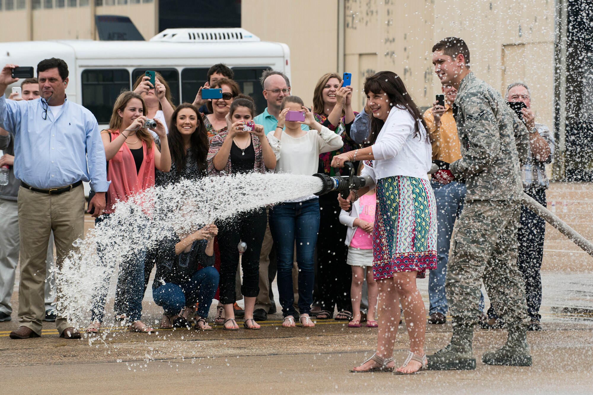 The wife of U.S. Air Force Lt. Col. Jeffrey Stogsdill fires up the water hose to spray down her husband after his return from a mission on April 24, 2015, Barksdale Air Force Base, La. Stogsdill is a B-52H Stratofortress pilot and is retiring from the Air Force Reserve. (U.S. Air Force photo by Master Sgt. Greg Steele/Released)