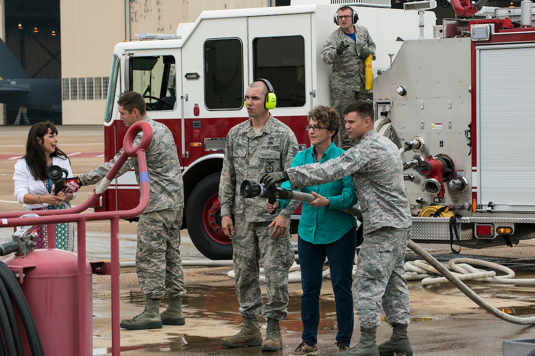 The wives of U.S. Air Force Lt. Cols. Jeffrey Stogsdill and David Knesek are shown how to use a fire hose as they wait for their husbands exit from a 307th Bomb Wing B-52H Stratofortress on April 24, 2015, Barksdale Air Force Base, La. Stogsdill and Knesek are flying their last mission before retiring from the Air Force Reserve. (U.S. Air Force photo by Master Sgt. Greg Steele/Released)