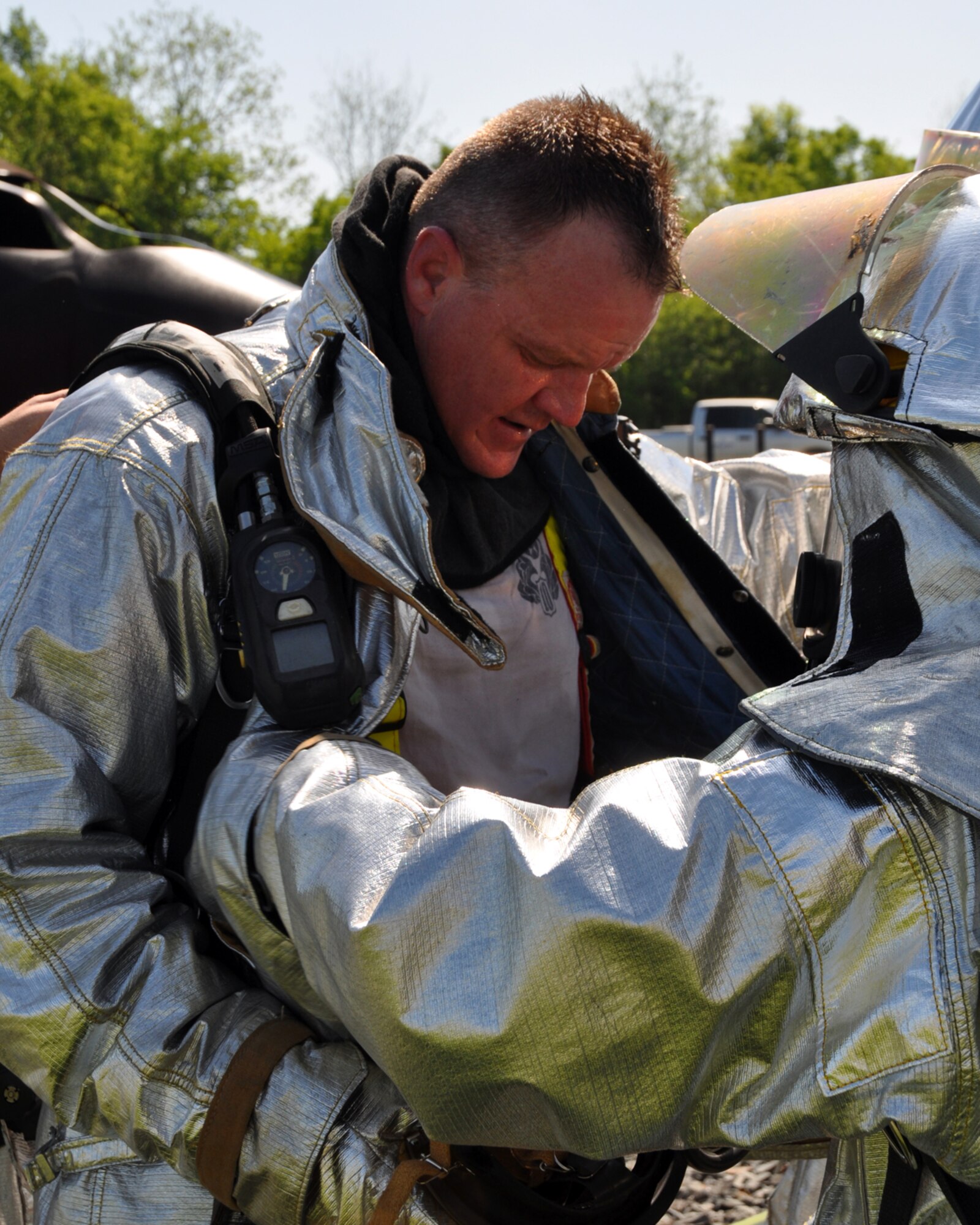 U.S. Air Force Col. Bruce Cox, commander of the 307th Bomb Wing at Barksdale Air Force Base, La., gets assistance in removing firefighting gear after taking part in a burning aircraft exercise with the 307th Civil Engineer Squadron firefighters during the May Unit Training Assembly. The firefighters instructed the commander on how to handle a hose to extinguish a fire on an aircraft fire training simulator. Barksdale Air Force Base is one of the bases equipped with an aircraft fire training simulator allowing firefighters to recreate different emergency scenarios without burning up an aircraft every time they practice. (U.S. Air Force photo by Master Sgt. Laura Siebert/Released)