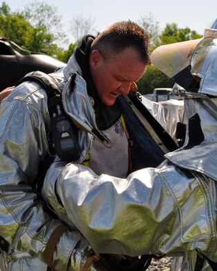 U.S. Air Force Col. Bruce Cox, commander of the 307th Bomb Wing at Barksdale Air Force Base, La., gets assistance in removing firefighting gear after taking part in a burning aircraft exercise with the 307th Civil Engineer Squadron firefighters during the May Unit Training Assembly. The firefighters instructed the commander on how to handle a hose to extinguish a fire on an aircraft fire training simulator. Barksdale Air Force Base is one of the bases equipped with an aircraft fire training simulator allowing firefighters to recreate different emergency scenarios without burning up an aircraft every time they practice. (U.S. Air Force photo by Master Sgt. Laura Siebert/Released)