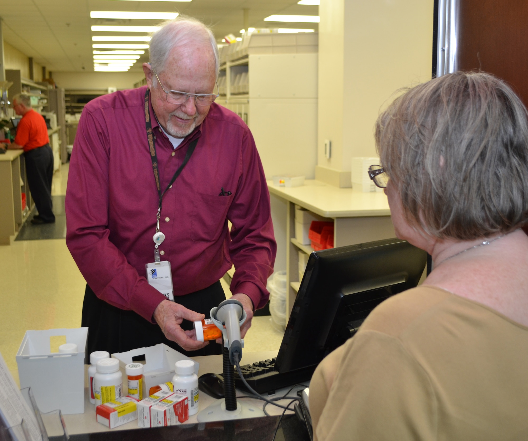 Retired Lt. Col. James Monsees, a volunteer at the Tinker Pharmacy, helps patient Joyce Peterson with her prescriptions. (Air Force photo by Ron Mullan/Released)