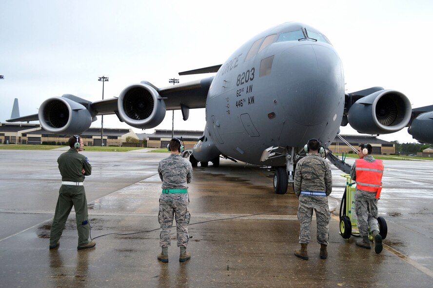 Air Force Airmen observe a C-17 Globemaster III aircraft from the 62nd Airlift Wing, Joint Base Lewis-McChord, Wash., while starting its engines before a Combined Joint Operational Access Exercise 15-01 sortie on Apr. 16, 2015, Pope Army Airfield, N.C. CJOAX 15-01 is an 82nd Airborne Division-led bilateral training event at Fort Bragg, N.C., from April 13-20, 2015. This is the largest exercise of its kind held at Fort Bragg in nearly 20 years and demonstrates interoperability between U.S. and U.K. Army soldiers and U.S. Air Force, Air National Guard, Royal Air Force Airmen and U.S. Marines. (U.S. Air Force photo/Marvin Krause)
