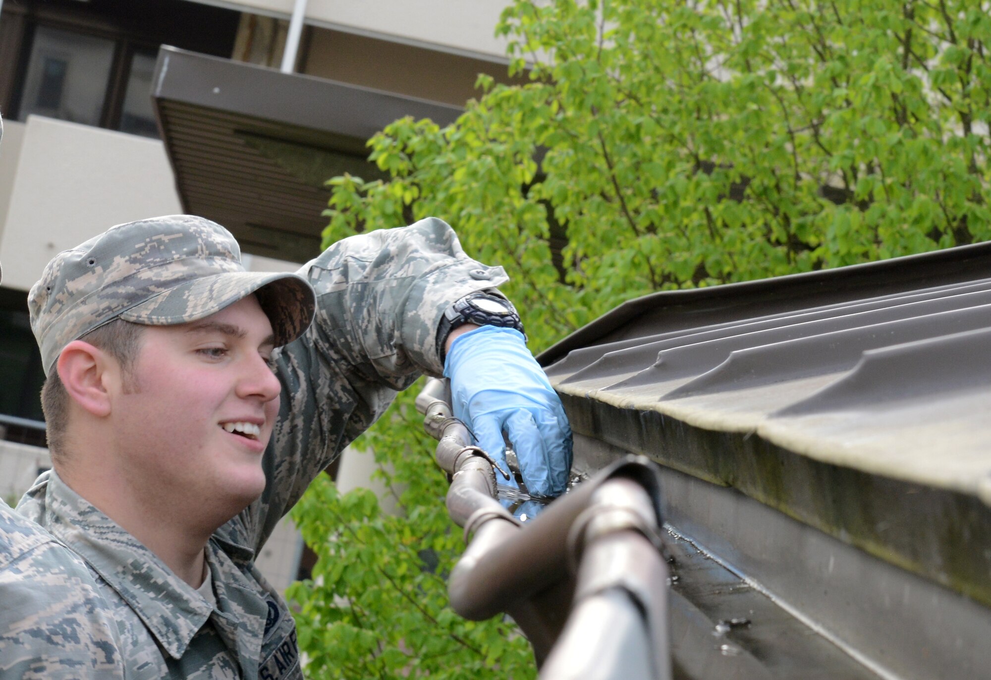 An Airman cleans out the gutter of a pavilion during Base Pride April 28, 2015, at Ramstein Air Base, Germany.  Airmen living in the dormitories and base housing cleaned the buildings and the surrounding areas where they lived in order to keep the base clean. (U.S. Air Force photo/Airman 1st Class Tryphena Mayhugh)