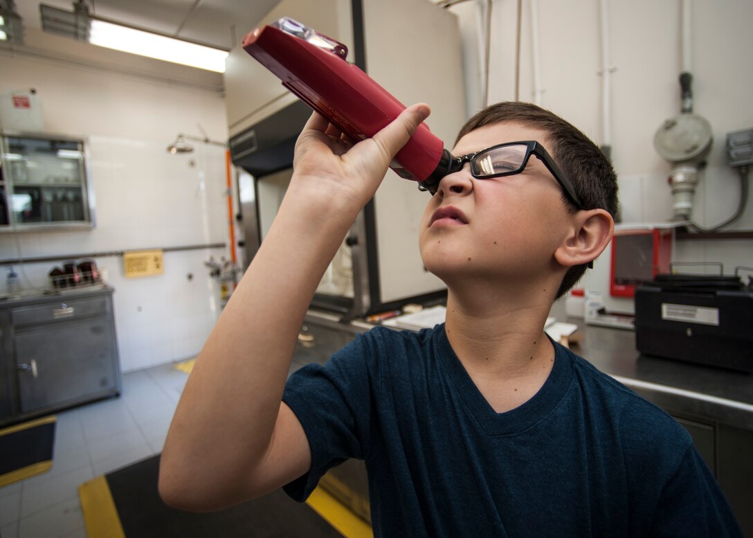 A 39th Air Base Wing dependent looks through a refractometer during the 2015 Job Shadow Day April 24, 2015, at Incirlik AB, Turkey. The refractometer is used to look for debris in the fuels sample taken from one of the 39th Logistics Readiness Squadron’s fuels truck. (U.S. Air Force photo by Airman 1st Class Cory W. Bush/Released)