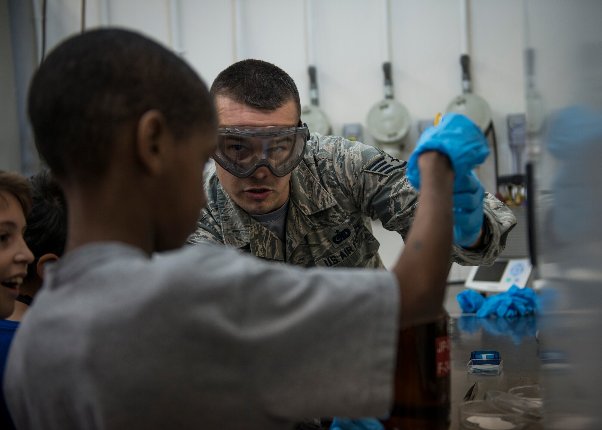 Staff Sgt. Timothy Wiseman, 39th Logistics Readiness Squadron NCO in charge of fuels laboratory, shares the results of a fuels test with Joseph, 39th Air Base Wing dependent, during the 2015 Job Shadow Day April 24, 2015, at Incirlik Air Base, Turkey. During their time in the fuels laboratory the dependents went step-by-step in the fuel sample testing process to ensure the samples meet Air Force standards. (U.S. Air Force photo by Airman 1st Class Cory W. Bush/Released)
