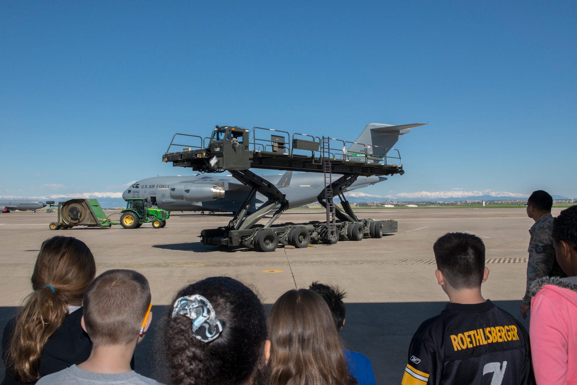 Dependents from the 39th Air Base Wing watch a Tunner 60K aircraft cargo loader and transporter demonstration during the 2015 Job Shadow Day April 24, 2015, at Incirlik Air Base, Turkey. Airmen from the 728th Air Mobility Squadron demonstrated for the children that the Tunner can carry up to six cargo pallets at once, as well as load and unload cargo from all military and commercial cargo aircraft. (U.S. Air Force photo by Airman 1st Class Cory W. Bush/Released)