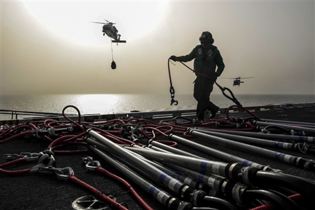 A U.S. sailor organizes cargo retrieval cables on the flight deck after MH-60S Seahawk helicopters transfers cargo to the aircraft carrier USS Theodore Roosevelt during a vertical replenishment in the U.S. 5th Fleet Area of Operation, April 29, 2015. 