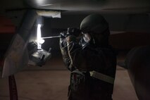 A crew chief performs night maintenance on an F-16 Fighting Falcon while wearing full protective gear during Exercise Beverly Midnight 15-3 at Kunsan Air Base, Republic of Korea, May 2, 2015. During exercises, maintenance wing inspection team members test maintenance professionals on their ability to safely launch jets while simultaneously responding to exercise injects, such as unexploded ordnance and administering Self Aid Buddy Care to wounded Airmen. (U.S. Air Force photo by Senior Airman Taylor Curry/Released)