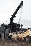 Soldiers assigned to the 207th Combat Support Company of the Alaska Army National Guard from left to right, Staff Sgt. Joseluis Villasenor, a wheeled vehicle mechanic, Staff Sgt. Edwin Brunner, a motor transport operator, and Spc. Ryan Graney, a wheeled vehicle mechanic, release the Heavy Expanded Mobility Tactical Truck (HEMTT) Wrecker crane hook from a rusted vehicle at Goose Bay State Game Refuge Oct. 17, 2010. About 60 Alaska National Guard Soldiers and recruits joined efforts with the state's Department of Fish and Game to clean up an estimated 20 tons from the dumpsite, which included eight abandoned vehicles.