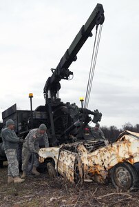 Soldiers assigned to the 207th Combat Support Company of the Alaska Army National Guard from left to right, Staff Sgt. Joseluis Villasenor, a wheeled vehicle mechanic, Staff Sgt. Edwin Brunner, a motor transport operator, and Spc. Ryan Graney, a wheeled vehicle mechanic, release the Heavy Expanded Mobility Tactical Truck (HEMTT) Wrecker crane hook from a rusted vehicle at Goose Bay State Game Refuge Oct. 17, 2010. About 60 Alaska National Guard Soldiers and recruits joined efforts with the state's Department of Fish and Game to clean up an estimated 20 tons from the dumpsite, which included eight abandoned vehicles.